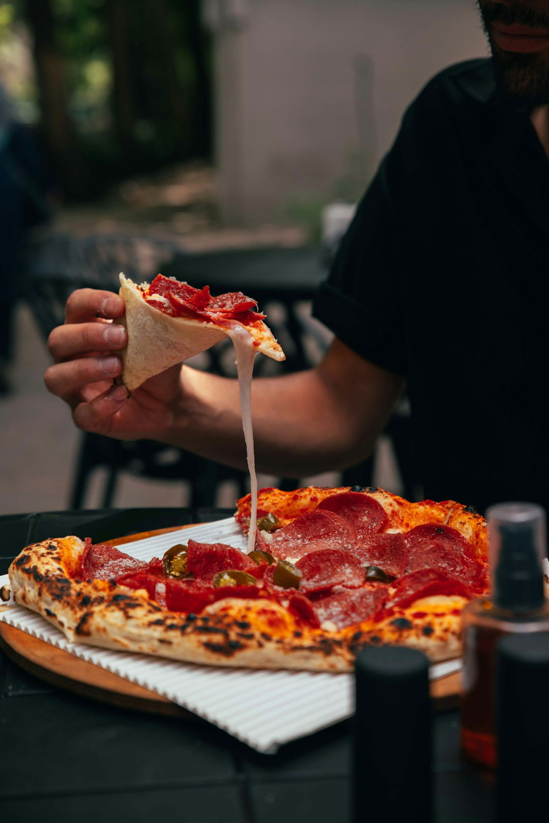 a man eating a slice of pepperoni pizza